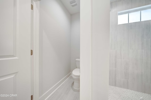 bathroom featuring a tile shower and toilet