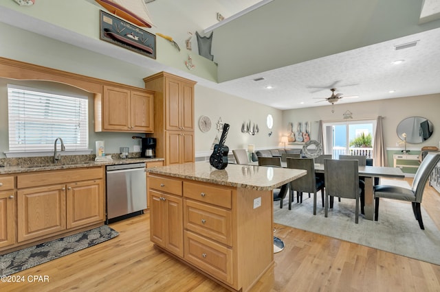 kitchen with stainless steel dishwasher, ceiling fan, sink, light hardwood / wood-style floors, and a kitchen island