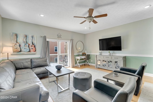 living room featuring ceiling fan, a textured ceiling, and light wood-type flooring