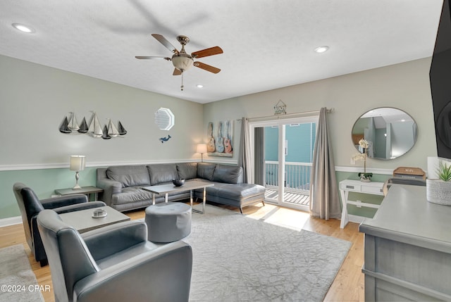 living room with a textured ceiling, light hardwood / wood-style floors, and ceiling fan