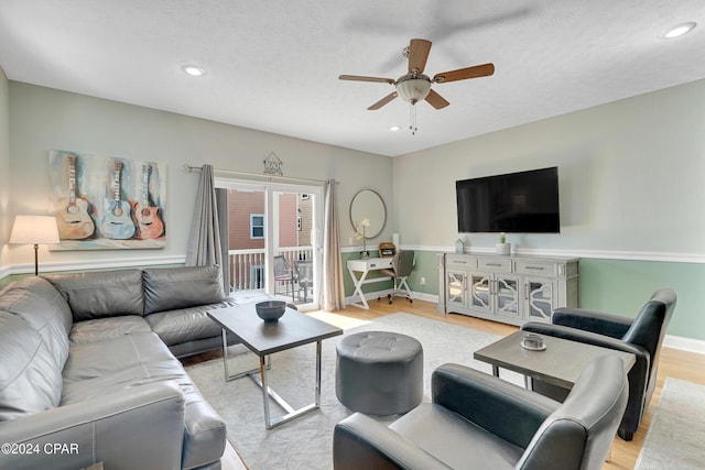 living room with a textured ceiling, ceiling fan, and light hardwood / wood-style flooring