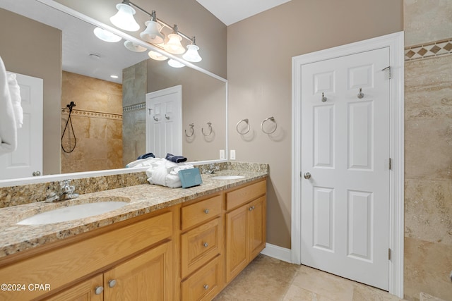 bathroom featuring tile patterned flooring, vanity, and a tile shower