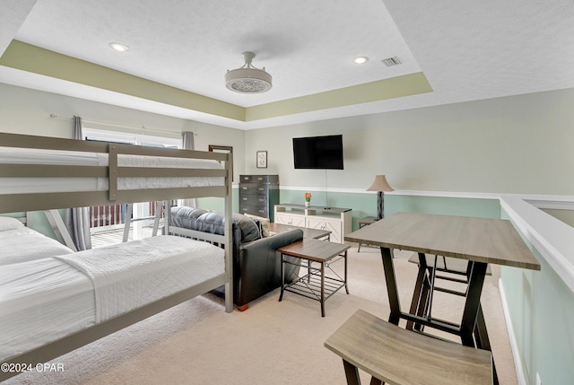 carpeted bedroom featuring a tray ceiling and a textured ceiling