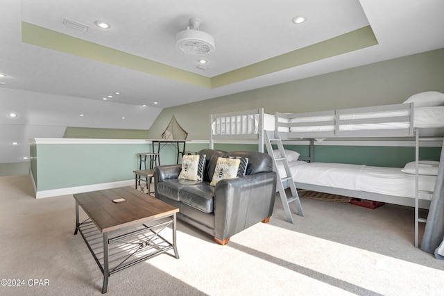 bedroom featuring light colored carpet and a raised ceiling