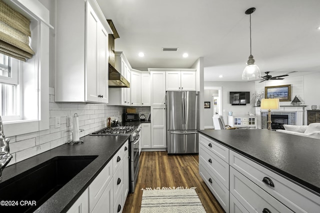 kitchen featuring white cabinetry, a brick fireplace, dark hardwood / wood-style floors, decorative light fixtures, and appliances with stainless steel finishes