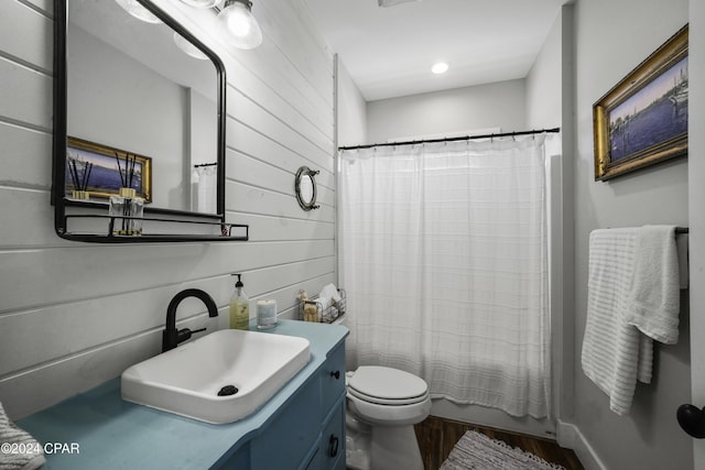 full bathroom with vanity, wood walls, hardwood / wood-style flooring, toilet, and shower / bath combo with shower curtain