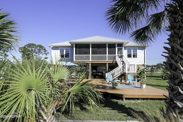 rear view of house with a yard, a sunroom, and a wooden deck