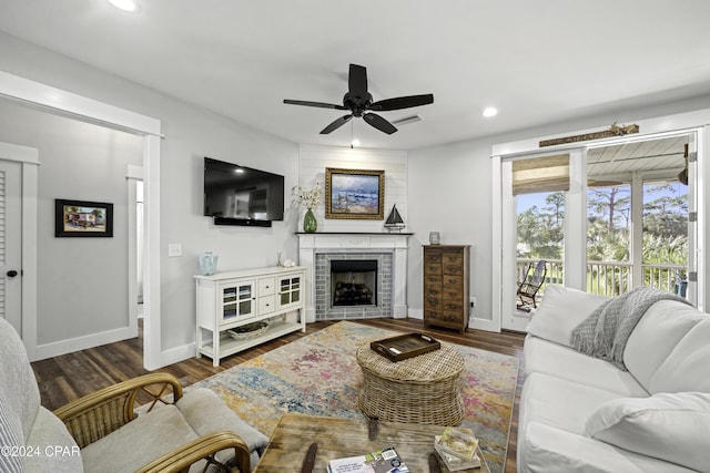 living room featuring a fireplace, ceiling fan, and dark wood-type flooring