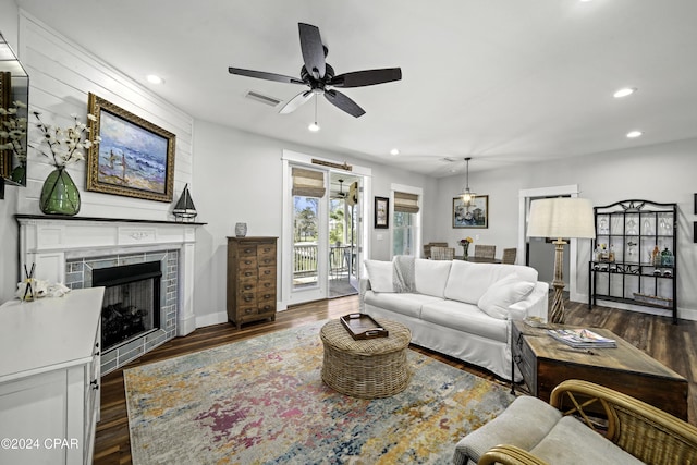 living room with a fireplace, ceiling fan, and dark hardwood / wood-style flooring