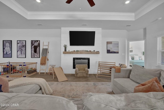 living room with a tray ceiling, ornamental molding, and ceiling fan