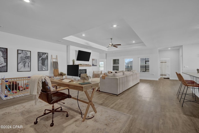 living room featuring ceiling fan, wood-type flooring, and a raised ceiling