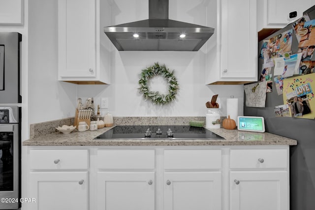 kitchen with white cabinetry, fridge, stainless steel oven, black electric stovetop, and wall chimney range hood