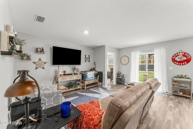 living room with a textured ceiling and light wood-type flooring