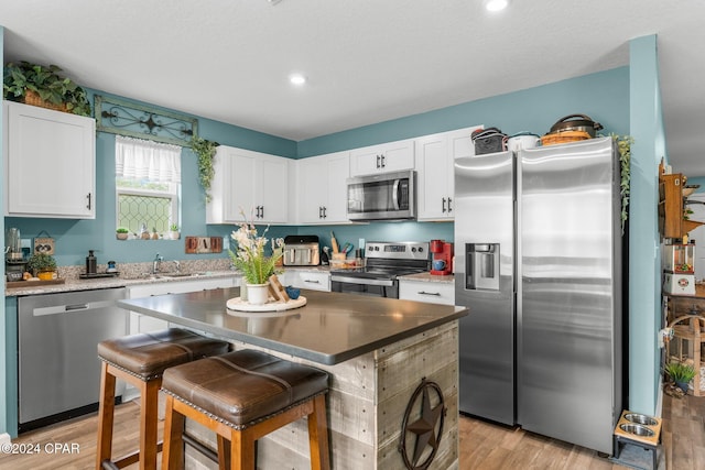 kitchen featuring a center island, white cabinets, light hardwood / wood-style floors, and appliances with stainless steel finishes