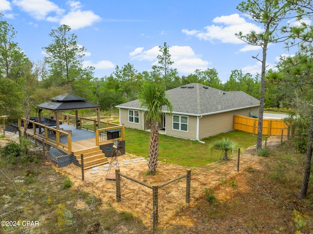 back of property with a gazebo, a deck, and a yard