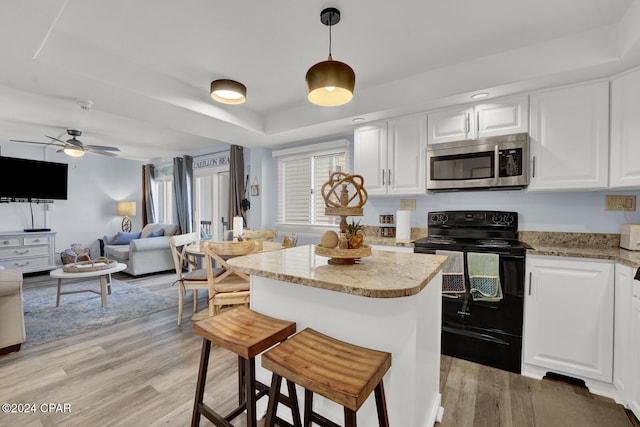 kitchen featuring black electric range oven, light hardwood / wood-style flooring, white cabinetry, plenty of natural light, and a breakfast bar area