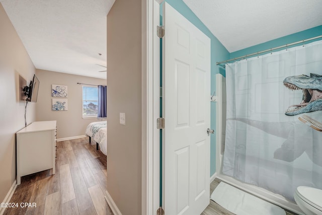 bathroom with curtained shower, wood-type flooring, a textured ceiling, and toilet