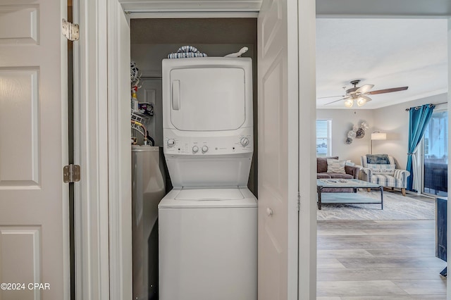 laundry area featuring stacked washer / dryer, a wealth of natural light, ceiling fan, and light hardwood / wood-style floors