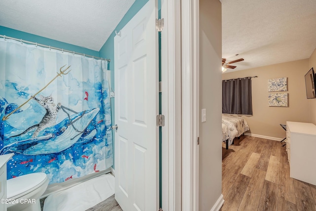 bathroom featuring ceiling fan, toilet, wood-type flooring, and a textured ceiling