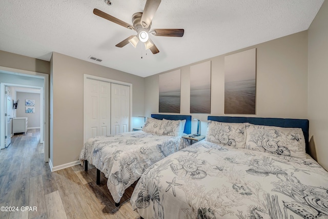 bedroom with a textured ceiling, light wood-type flooring, a closet, and ceiling fan