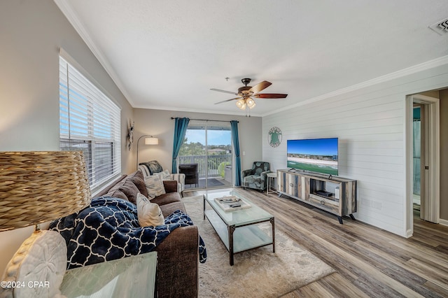 living room featuring hardwood / wood-style floors, ceiling fan, and crown molding