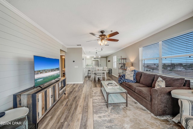 living room with wood-type flooring, ceiling fan, ornamental molding, and wood walls