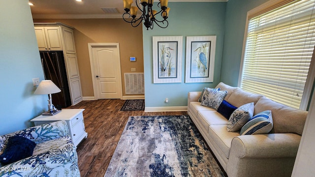 living room featuring dark hardwood / wood-style floors, ornamental molding, and an inviting chandelier