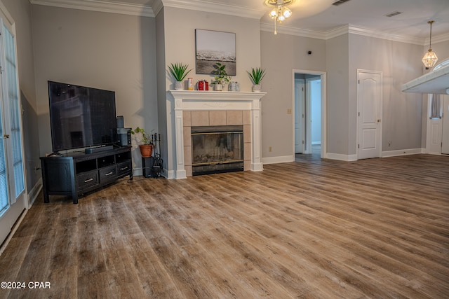 unfurnished living room with wood-type flooring, ornamental molding, and a tiled fireplace