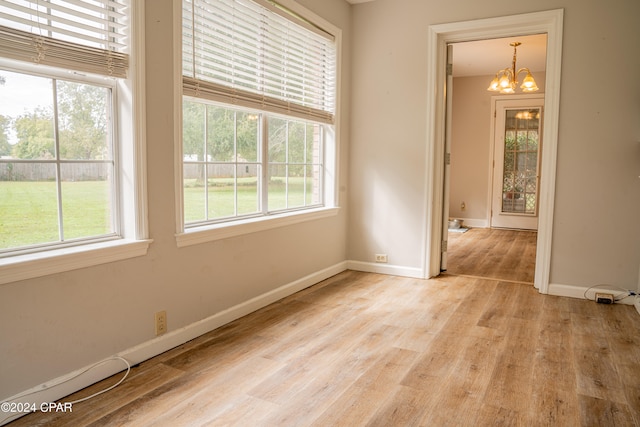 spare room featuring a chandelier and light hardwood / wood-style flooring