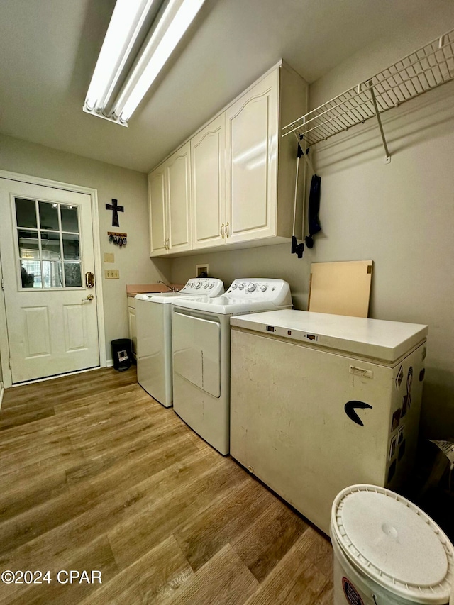 washroom with washing machine and dryer, cabinets, and light hardwood / wood-style floors