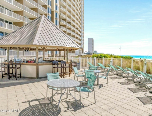 view of patio with a gazebo, a water view, and a grill