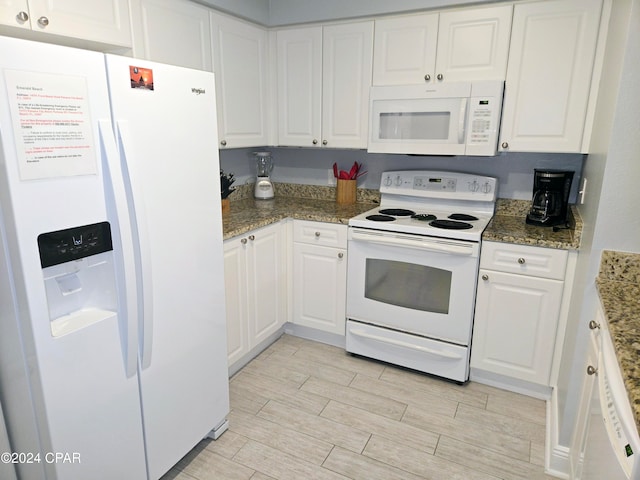 kitchen with white cabinetry, dark stone counters, and white appliances