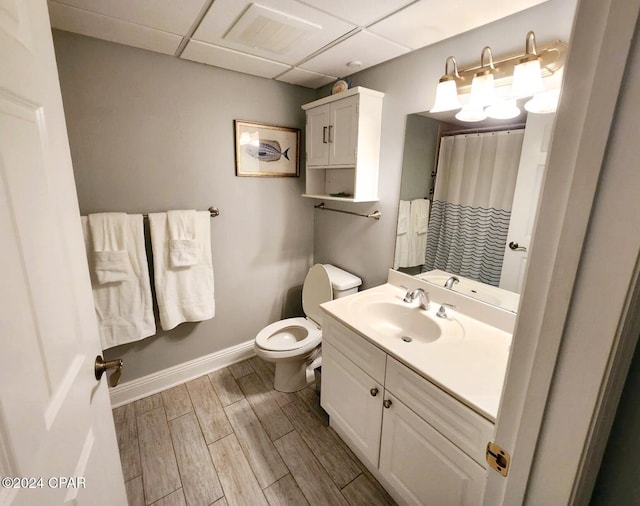 bathroom with a paneled ceiling, toilet, vanity, and hardwood / wood-style flooring