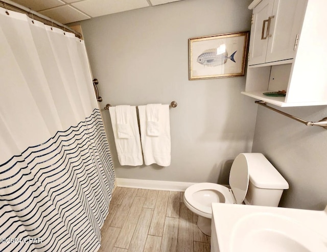 bathroom featuring a shower with curtain, a drop ceiling, wood-type flooring, and toilet