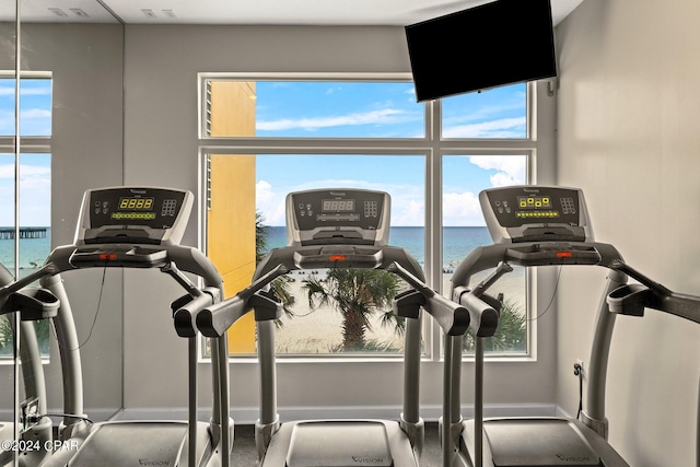 exercise room featuring a water view and a wealth of natural light