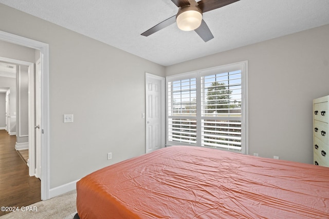 bedroom with ceiling fan, wood-type flooring, and a textured ceiling