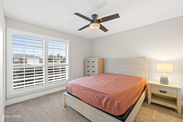 bedroom with ceiling fan, light carpet, and a textured ceiling