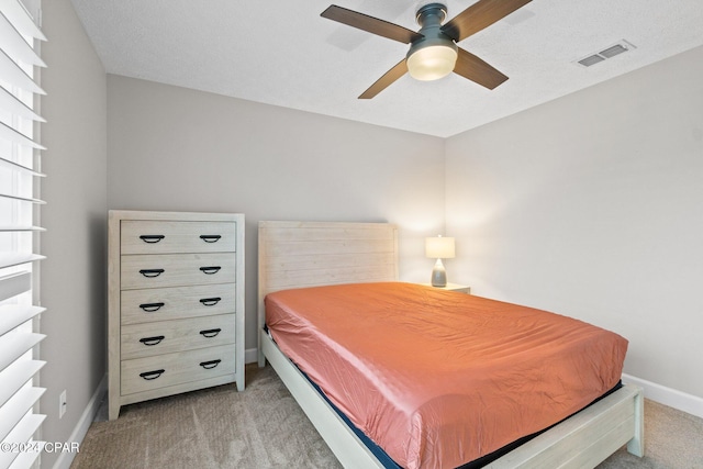 carpeted bedroom with ceiling fan and a textured ceiling