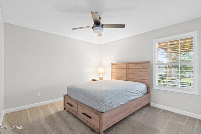 bedroom with a textured ceiling, ceiling fan, and light carpet