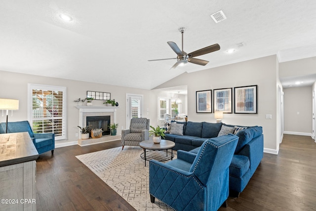 living room featuring a textured ceiling, a tiled fireplace, dark wood-type flooring, and vaulted ceiling