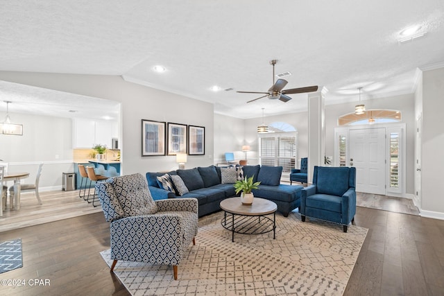 living room with a textured ceiling, lofted ceiling, light wood-type flooring, and crown molding