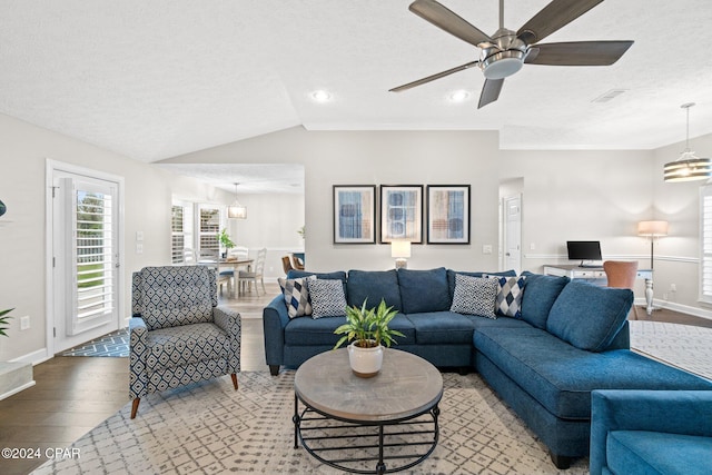 living room featuring a textured ceiling, ceiling fan with notable chandelier, wood-type flooring, and vaulted ceiling