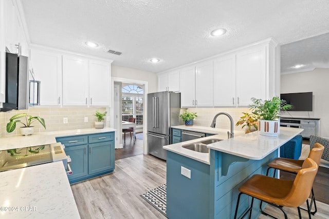 kitchen featuring high end fridge, sink, white cabinets, light hardwood / wood-style floors, and a breakfast bar area