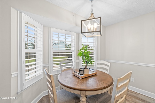 dining area with hardwood / wood-style floors, a textured ceiling, and a chandelier