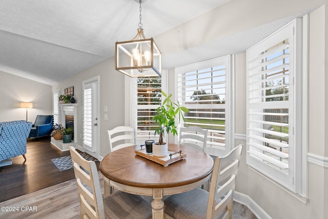 dining room featuring a textured ceiling, a notable chandelier, vaulted ceiling, and hardwood / wood-style flooring