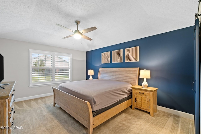 carpeted bedroom featuring ceiling fan and a textured ceiling