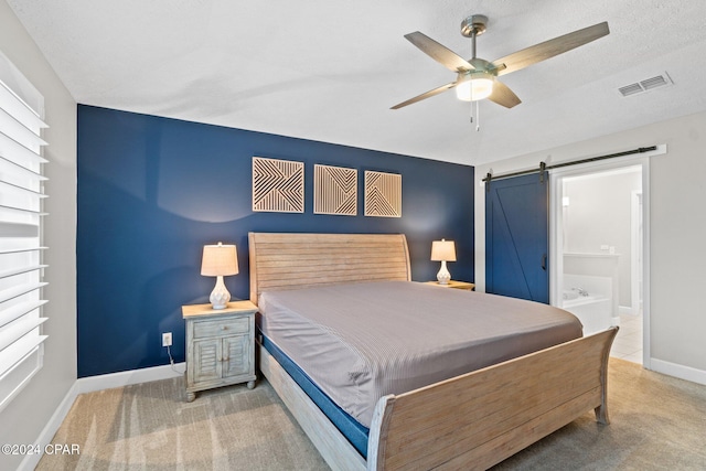 carpeted bedroom featuring a textured ceiling, a barn door, ceiling fan, and connected bathroom