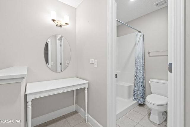 bathroom with tile patterned flooring, toilet, walk in shower, and a textured ceiling