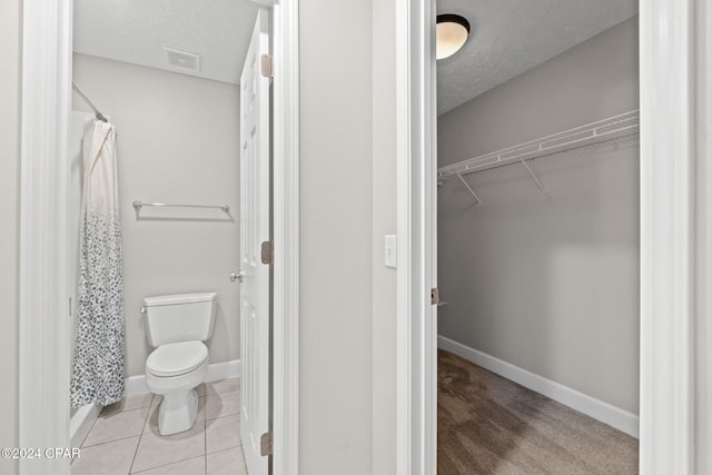 bathroom with tile patterned flooring, a textured ceiling, and toilet