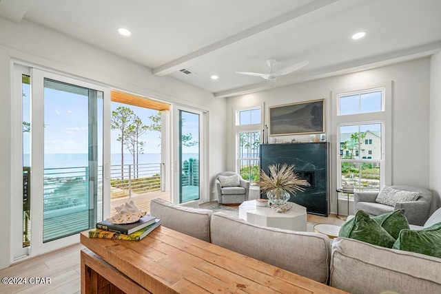 living room with a wealth of natural light, light hardwood / wood-style flooring, a water view, and ceiling fan